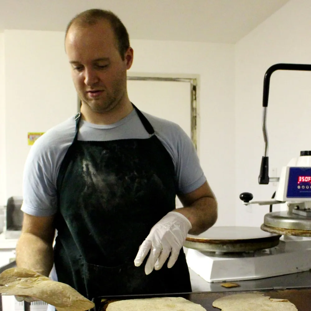 Marshall pressing fresh tortillas on the line.