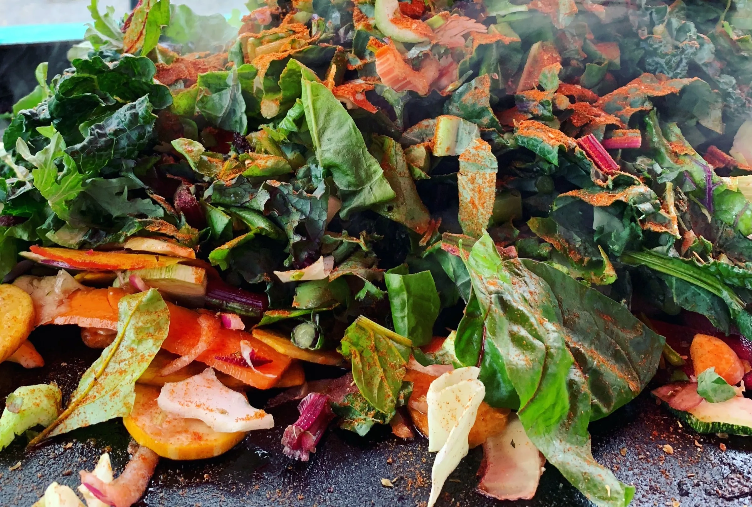 Chard, carrots and beet slices searing together on a flat-top griddle.